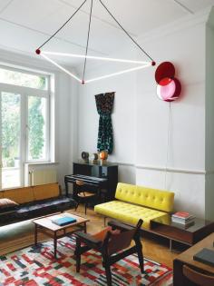 Located just off the entry hall, this room opens onto a lush garden. The residents commissioned the overhead light from designers Sylvain Willenz and Hubert Verstraeten. “The use of red billiard ball references Charles and Ray Eames’s Hang-It-All coat rack,” says Smith. The wall-hung light is by the contemporary São Paulo–based designers Luciana Martins and Gerson de Oliveira. The rug is a Moroccan patchwork from the 1960s