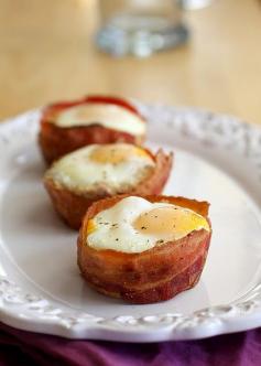 Bacon and Egg Toast Cups Directions: Preheat the oven to 400° F. Spray large muffin pan with cooking spray. In a frying pan, cook bacon about 3-5 minutes, until partially cooked but not completely crispy (if using precooked bacon skip this step). Transfer to a paper towel-lined plate. Cut out circles (about 3 1/2 inches) in each piece of bread using a cookie cutter or a drinking glass turned upside down. Press the bread rounds into the greased muffin wells. Curl a piece of bacon around the periphery of each piece of bread, positioning it between the bread and the muffin tin to help keep it in position. This can be a little tricky until you get the hang of it. Sprinkle a small amount of shredded cheese in the center of each piece of bread. Crack one egg over each piece of bread being careful not to break the yolks. You may not want to use all of the egg white. If you do you may need to adjust the cooking time to a little longer. Once all the bread pieces have been topped with eggs, bake until eggs are cooked through to your liking (about 15 minutes for me) and bacon is crispy. Run a knife around the edge of each muffin well and pop the egg cups out. Season with salt and pepper to taste and serve immediately.